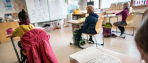 Schulkinder sitzen in einem Klassenraum an ihren Tischen. (Symbolbild)