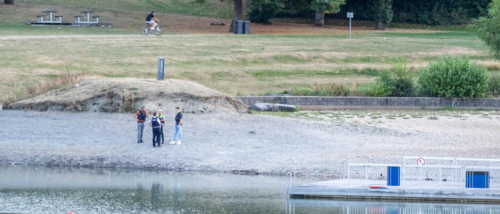 Polizisten stehen am Ufer des Badesees, an dem sich das Unglück ereignete.