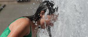 Eine junge Frau kühlt sich Anfang August in einem Citybrunnen in Berlin ab.