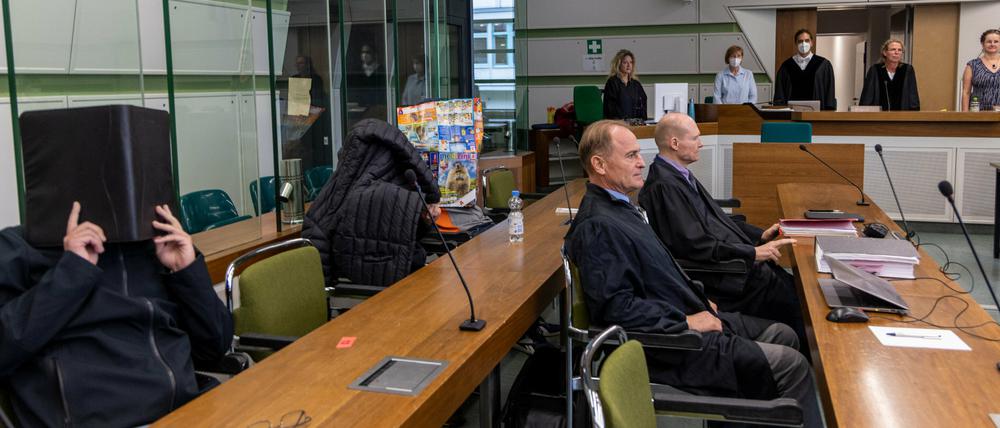 Die Angeklagten sitzen im Gerichtssaal des Kriminalgerichts Moabit hinter ihren Anwälten und verdecken ihre Gesichter.