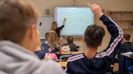 In einer 9. Klasse erklärt eine Lehrerin geometrische Figuren am Smartboard, Schüler:innen melden sich.
