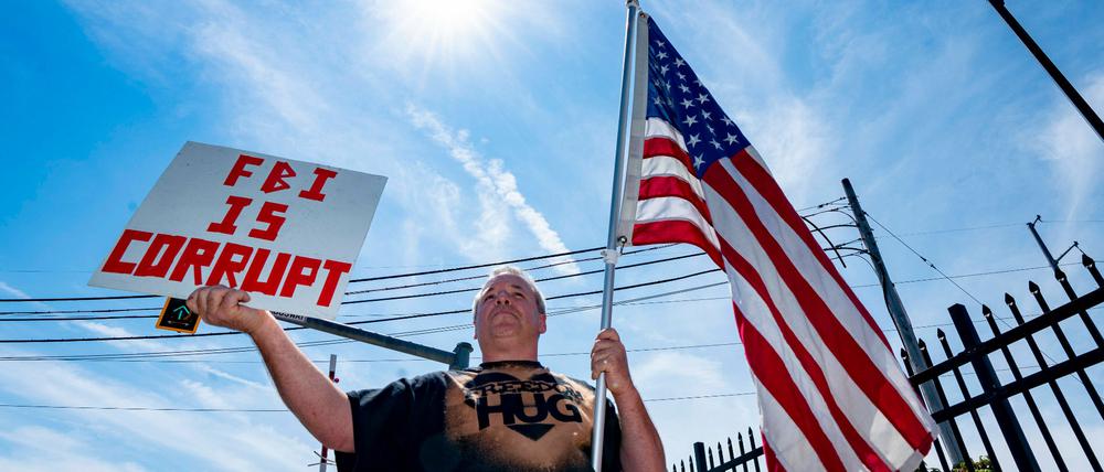 Ein Demonstrant hält in Massachusetts ein Schild und die amerikanische Flagge in die Höhe.