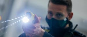 Ein Polizeibeamter demonstriert einen Schuss mit einem Distanzelektroimpulsgerät (DEIG oder auch Taser).