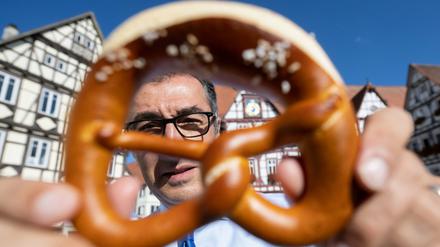 Bundesernährungsminister Cem Özdemir zeigt auf dem Marktplatz seines Geburtsorts eine Brezel. 