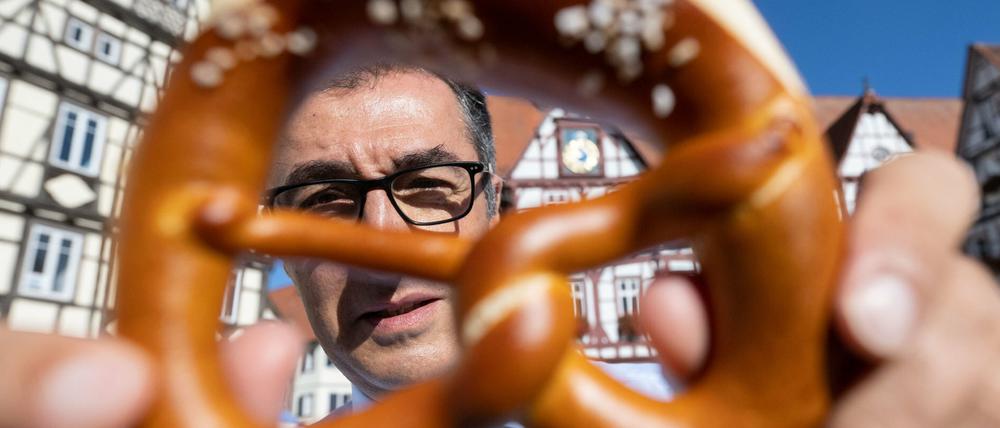 Bundesernährungsminister Cem Özdemir zeigt auf dem Marktplatz seines Geburtsorts eine Brezel.