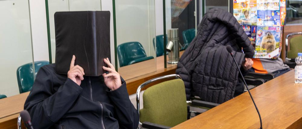 Die Angeklagten verdecken im Gerichtssaal des Kriminalgerichts Moabit ihre Gesichter.