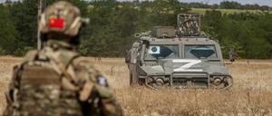 Ein russischer Soldat steht in der Ukraine vor einem Armeefahrzeug.