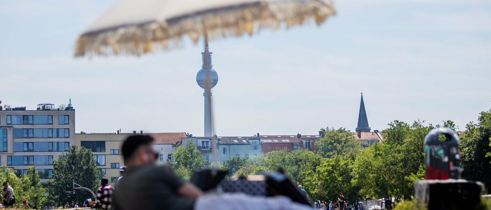 Ein Mann liegt im Mauerpark vor dem Berliner Fernsehturm unter einem Sonnenschirm (Symbolbild).
