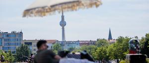 Ein Mann liegt im Mauerpark vor dem Berliner Fernsehturm unter einem Sonnenschirm (Symbolbild). 