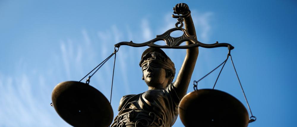 Eine Statue der Justitia hält eine Waage in ihrer Hand. 
