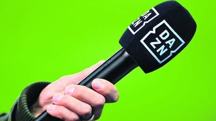 Ein Mikrofon des Kanals DAZN wird vor einen Greenscreen gehalten. (Symbolbild)