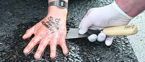 A police officer removes glue from the hand of a "Letzte Generation" (Last Generation) activist that reads "save oil instead of drill oil", blocking a road under the slogan "Let's stop the fossil madness!" for an end to fossil fuels and against oil drilling in the North Sea, in Berlin, Germany, July 15, 2022. REUTERS/Fabrizio Bensch