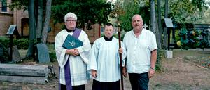 Pfarrer Olaf Tuszewski steht mit Georg Mesus und dessen Sohn Johannes (v.l.) auf dem Domfriedhof der St.-Hedwig-Gemeinde.