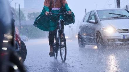 Radfahrer fahren bei starkem Regen durch die Stadt.
