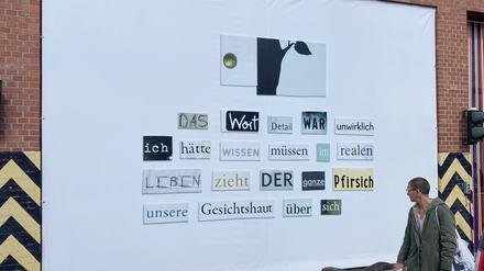 Eine Kollage aus ausgeschnittenen Wörtern von Herta Müller ist auf einem Werkstor auf dem Gelände der Uferhallen  zu sehen.  