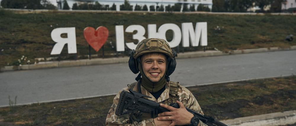 Ein ukrainischer Soldat lächelt vor einem Schild mit der Aufschrift „Ich liebe Izium“ in der befreiten Stadt Izium in der Region Charkiw. 