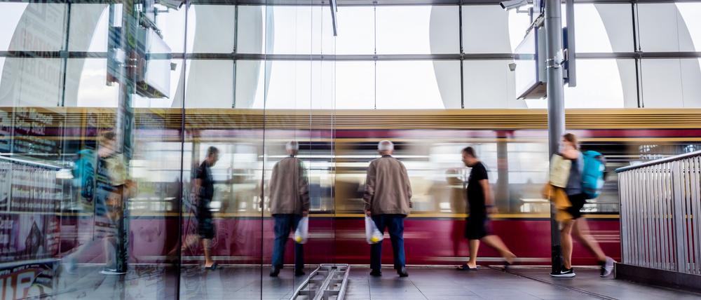 Eine S-Bahn fährt am Berliner Bahnhof Ostkreuz ein und spiegelt sich in einer Glasscheibe.
