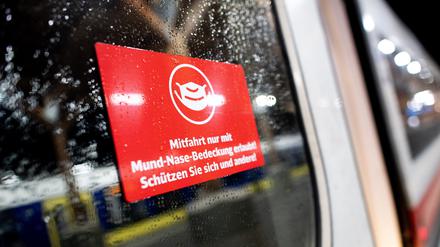 Ein Schild zur Maskenpflicht hängt an einer Zugtür. 