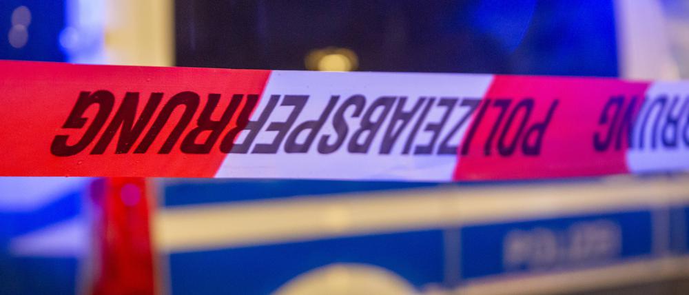  Symbolbild: Polizeiabsperrung mit Polizeiauto im Hintergrund. 