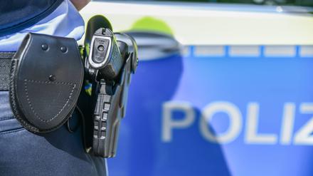 Eine Polizistin steht vor einem Polizeiwagen. (Symbolbild)