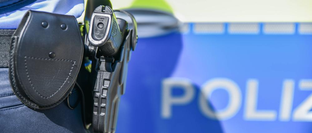 Eine Polizistin steht vor einem Polizeiwagen. (Symbolbild)