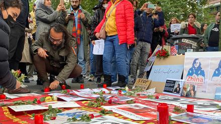 Nach der Kundgebung legen Teilnehmende in Gedanken an Jina Mahsa Amini Blumen nieder.