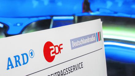  Symbolbild Rundfunkbeitrag: Briefkopf vor laufendem Fernsehgerät.
