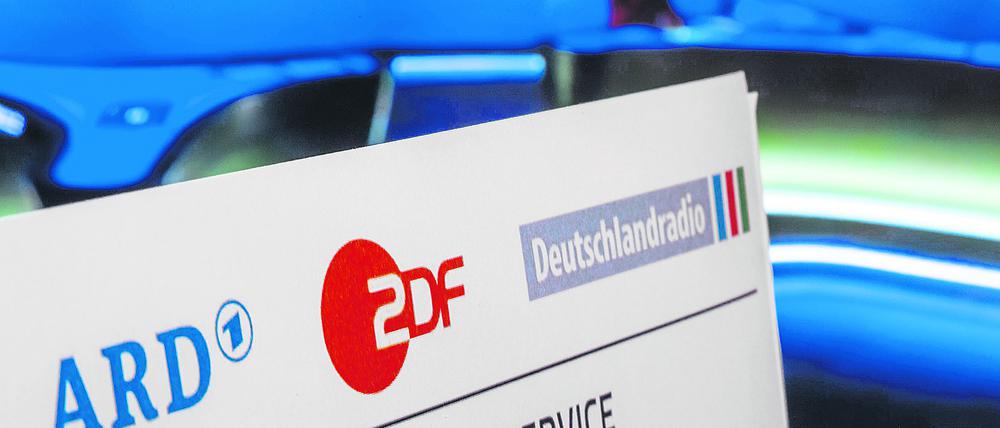  Symbolbild Rundfunkbeitrag: Briefkopf vor laufendem Fernsehgerät.