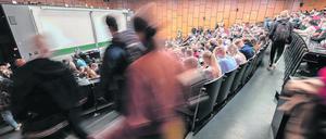 Studierende suchen sich in einem vollbesetzen Hörsaal einen freien Sitzplatz.