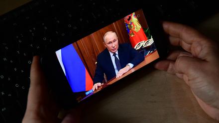Ein Person schaut sich die Putin-Rede auf einem Mobiltelefon an.