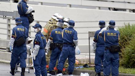 Polizisten und Feuerwehrleute untersuchen die Stelle, an der sich ein Mann aus Protest für das Staatsbegräbnis anzündete.     
