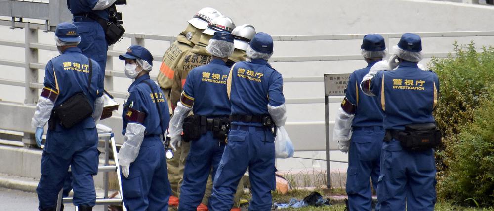 Polizisten und Feuerwehrleute untersuchen die Stelle, an der sich ein Mann aus Protest für das Staatsbegräbnis anzündete.