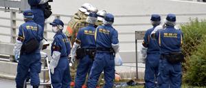 Polizisten und Feuerwehrleute untersuchen die Stelle, an der sich ein Mann aus Protest für das Staatsbegräbnis anzündete.