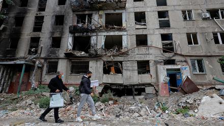 Mitglieder einer Wahlkommission laufen am 24. September vor einem zerstörten Gebäude in Mariupol vorbei.