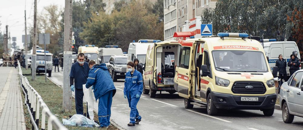 Rettungskräfte stehen nach der Tat auf einer Straße in Ischewsk. 