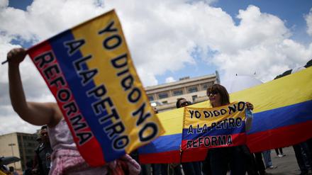 Demonstrierende in Bogota halten Plakate und Fahnen in die Luft.