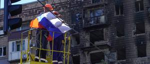 Ein Arbeiter befestigt eine russische Flagge in Mariupol.