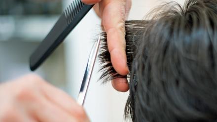 ARCHIV - 29.04.2021, Berlin: Ein Friseur schneidet in einem Friseur-Salon einer Kundin mit einer Schere die Haare. Von der Erhöhung des Mindestlohns in Deutschland am 1. Oktober profitieren nach einer neuen Studie rechnerisch 6,64 Millionen Menschen in Deutschland. (zu dpa «Studie: 6,64 Millionen profitieren von höherem Mindestlohn») Foto: Symbolbild Friseur/dpa +++ dpa-Bildfunk +++