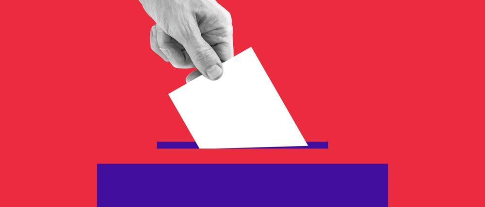 The human hand drops the ballot into the box.