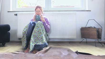 Eine Frau sitzt vor einer Heizung.