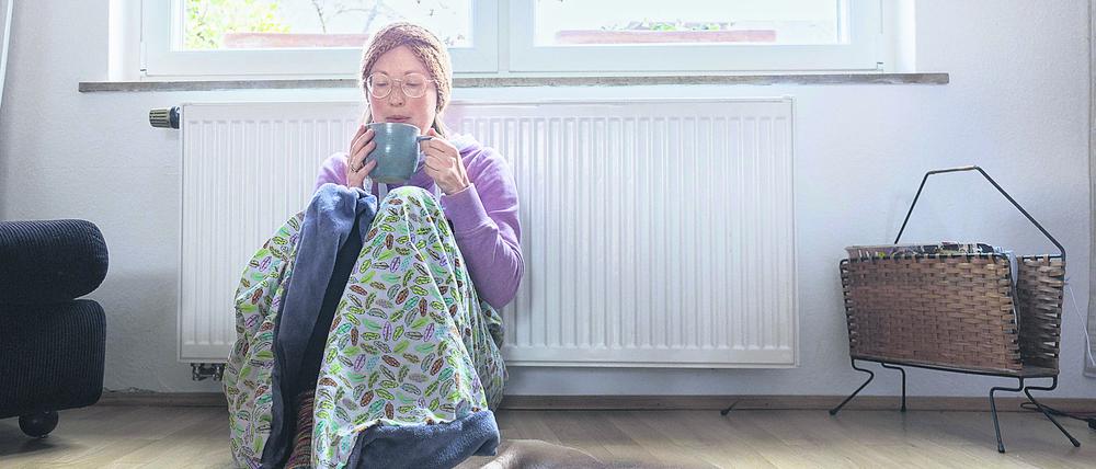 Eine Frau sitzt vor einer Heizung.