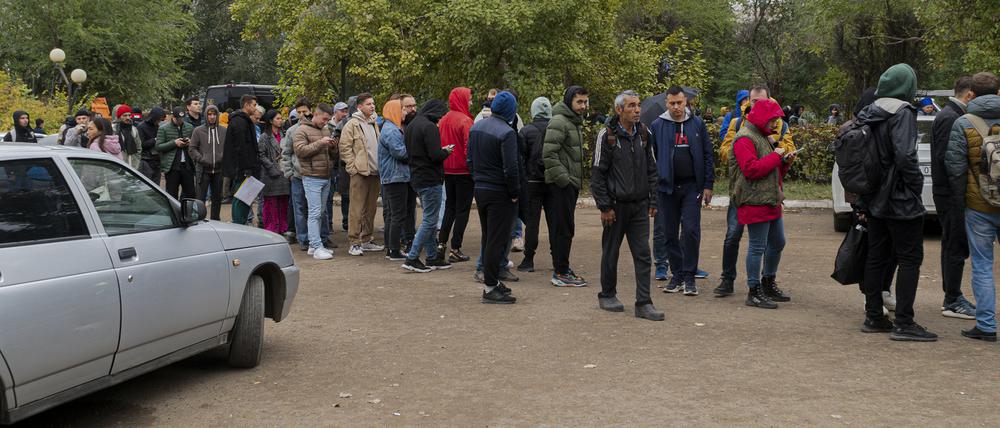 Russen, hauptsächlich Männer, stellen sich an, um eine kasachische Registrierung zu erhalten.