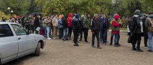 Russen, hauptsächlich Männer, stellen sich an, um eine kasachische Registrierung zu erhalten.
