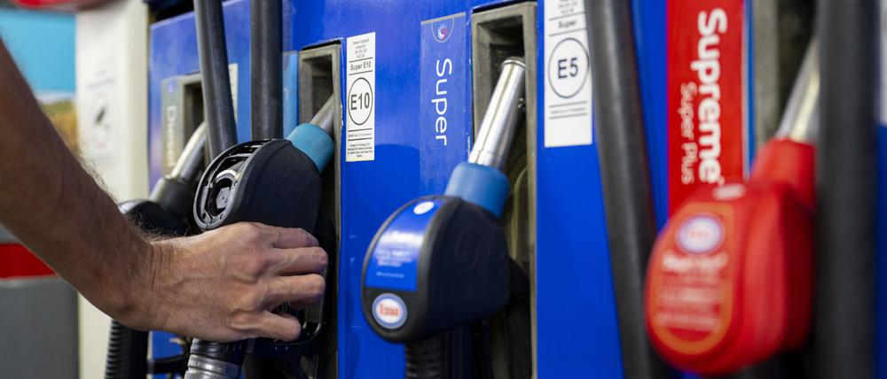 Ein Autofahrer in München hängt an einer Tankstelle eine Zapfpistole in die Zapfsäule.