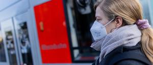 Eine Frau mit FFP2-Maske wartet auf ihre Straßenbahn.