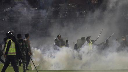 Polizisten und Soldaten stehen inmitten von Tränengasrauch bei einem Erstliga-Spiel zwischen Arema FC und Persebaya FC. 