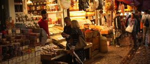 Ein Lebensmittelverkäufer spricht mit Kunden auf einem Straßenmarkt.