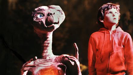 Henry Thomas als „Elliot“ und der Außerirdische „E.T.“ in einer Szene des gleichnamigen Fantasy-Films von Steven Spielberg. Das kleine Schrumpelwesen von einem fernen Planeten wird aus Versehen von seiner Raumschiff-Besatzung auf der Erde zurückgelassen, freundet sich mit einer Kindergruppe an und stiftet heillose Verwirrung. Sein größter Wunsch, „nach Hause“ zurückzukehren, geht nach einem Telefonat mit seinem Heimatplaneten in Erfüllung. „E.T.“ lief am 9. Dezember 1982 in den deutschen Kinos an und war so erfolgreich, dass er über zehn Jahre Platz eins der Liste der erfolgreichsten Filme anführte.
