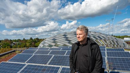 Blick über den Campus. Andreas Wanke auf dem Dach der Rost- und Silberlaube, das mit Solarzellen bestückt ist, im Hintergrund die Kuppel der Philologischen Bibliothek.