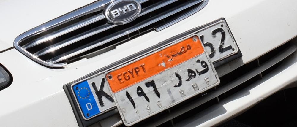 Ein Taxi mit einem alten deutschen Kennzeichen unter einem ägyptischen Kennzeichen steht in Kairo auf der Straße.
